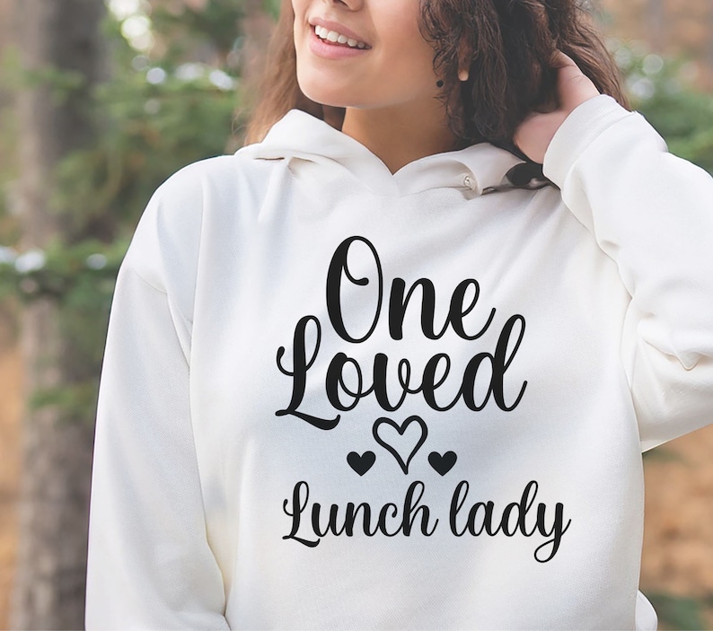 May include: White hoodie with black text that reads "One Loved Lunch Lady" with three small hearts.