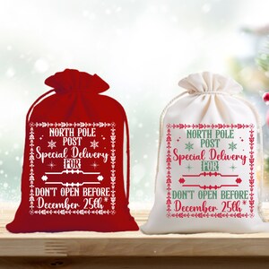 May include: Two Christmas gift bags, one red and one white, with a festive design. The bags have the text "North Pole Post Special Delivery For" and "Don't Open Before December 25th".
