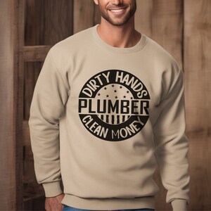 May include: Tan sweatshirt with a black circle graphic that says "Dirty Hands Plumber Clean Money".