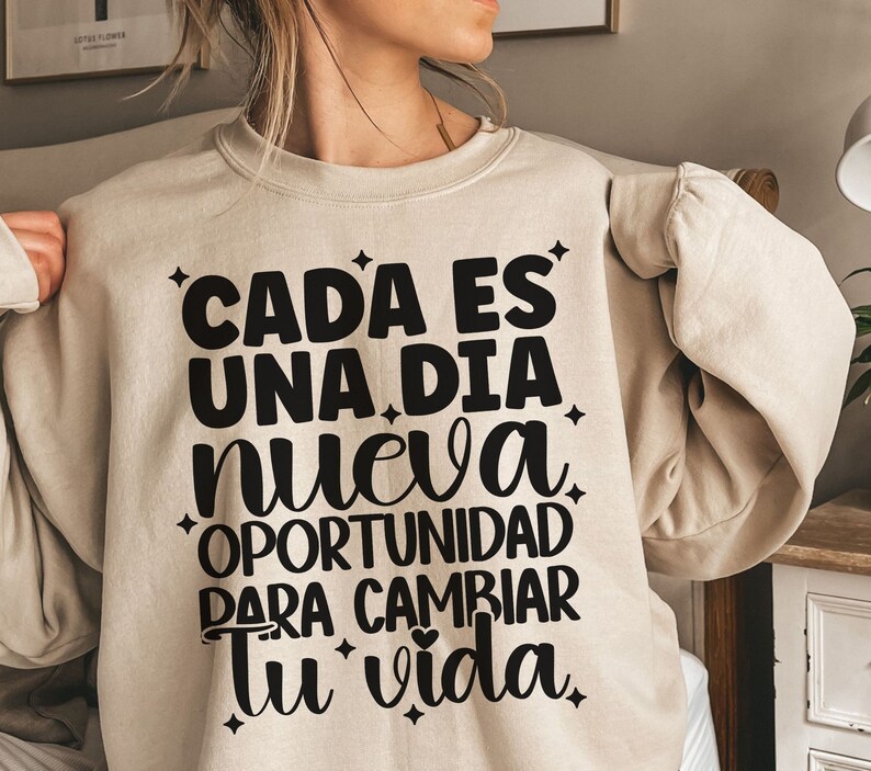 May include: Beige sweatshirt with black text that reads "Cada es una dia nueva oportunidad para cambiar tu vida".