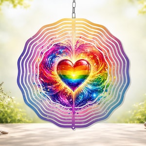 May include: A decorative wind spinner with a rainbow heart design. The heart is filled with vibrant colors, including red, orange, yellow, green, blue, and purple. The spinner has a layered, wavy edge in shades of purple and gold, suspended by a chain.