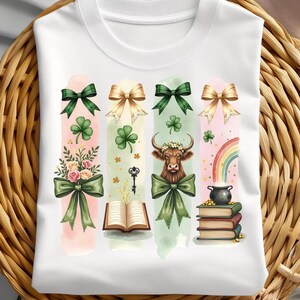 May include: White t-shirt with a green, gold, and pink design featuring a cow, a book, a key, a pot of gold, and a rainbow. The design is made up of four vertical panels with a watercolor effect.