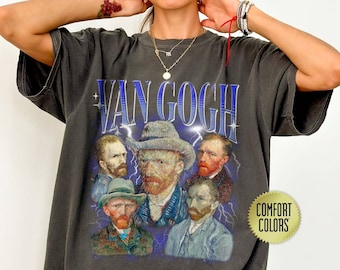 May include: A dark gray t-shirt with a vintage-style print of Vincent van Gogh's self-portrait and other portraits. The text "Van Gogh" is printed in blue above the portraits. The shirt has a "Comfort Colors" tag.
