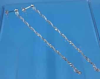May include: A pair of silver chain earrings with a simple stud design. The earrings are long and dangle, with a delicate chain link.