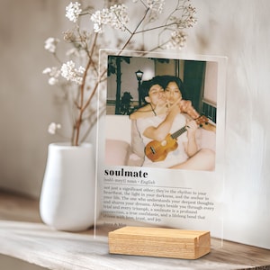 May include: A clear acrylic photo frame with a wood base. The frame holds a photo of a couple holding a ukulele. The text "soulmate" is printed below the photo with a definition of the word.