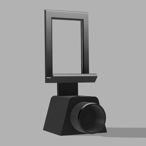 May include: A black phone stand with a built-in camera lens. The stand has a rectangular frame for holding a phone and a circular lens on the bottom.