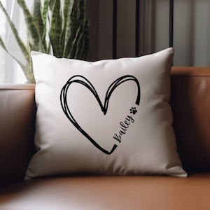 Peut inclure: Un oreiller blanc avec un motif de cœur noir et le nom "Bailey" écrit à l'intérieur du cœur. Une empreinte de patte se trouve à côté du nom.