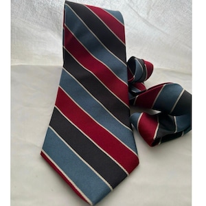 May include: A striped tie with a classic design. The tie features alternating diagonal stripes of burgundy, navy blue, black, and light blue, with thin white stripes. The tie is made of a smooth fabric.