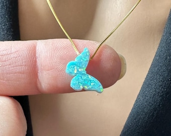 May include: A delicate gold chain necklace with a light blue opal butterfly pendant.