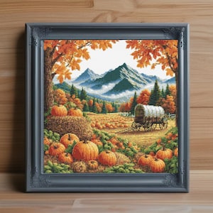 以下が含まれることがあります： 秋の収穫シーンを描いた額入りのクロスステッチアート。カボチャ畑、屋根付きのワゴン、背景の山々が特徴です。フレームは濃いグレーで、オレンジ、緑、茶色などの色使いです。
