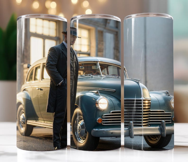 May include: A vintage blue car with chrome accents and a man in a suit and fedora standing next to it. The car has a long hood and a large grille. The man is looking at the camera.