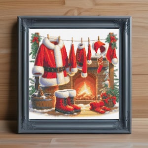 Puede incluir: Obra de arte enmarcada que representa una escena navideña. El traje, el sombrero y las botas rojas y blancas de Papá Noel se exhiben cerca de una chimenea. También hay un barril de madera y una cesta de vegetación. La obra está enmarcada.