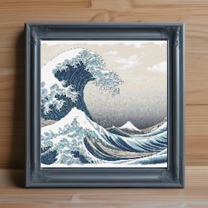 May include: Framed artwork featuring a pixelated depiction of Hokusai's "The Great Wave off Kanagawa." The image showcases a large, curling wave in shades of blue and white, with a mountain in the background. The artwork is set in a dark gray ornate frame.