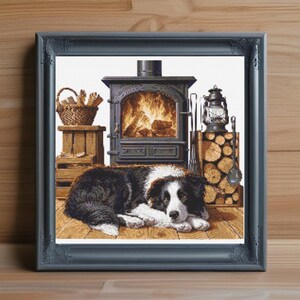 Könnte beinhalten: Gerahmtes Kunstwerk mit einem schwarz-weißen Border Collie, der vor einem Kamin auf einem Holzboden liegt. Ein Korb mit Brennholz und eine Laterne sind ebenfalls zu sehen. Der Kamin hat ein Feuer.