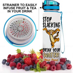 May include: White water bottle with a blue lid and a blue carrying strap. The bottle has a graphic of a cartoon tiger with the text "Stop Slacking Drink Your Water Your Name". The bottle has a strainer to infuse fruit and tea.