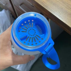 Pode incluir: Uma garrafa de &aacute;gua de pl&aacute;stico azul e transparente com um filtro embutido e uma al&ccedil;a de transporte azul.