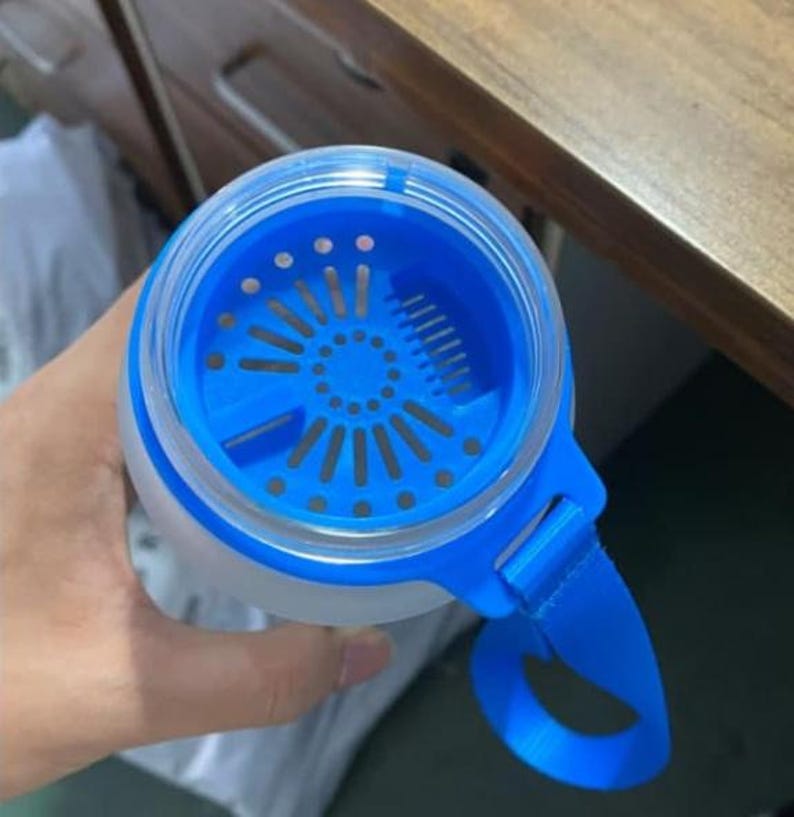 Pode incluir: Uma garrafa de &aacute;gua de pl&aacute;stico azul e transparente com um filtro embutido e uma al&ccedil;a de transporte azul.