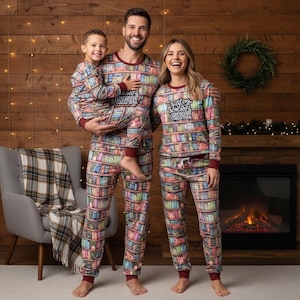 以下が含まれることがあります： 本棚柄のパジャマを着た家族。パジャマは長袖で、バーガンディのトリムと「One More Chapter」の文字が入っています。家族は暖炉と木の壁の前に立っています。