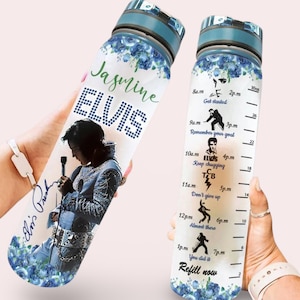 Könnte beinhalten: Eine durchsichtige Wasserflasche mit blauem Deckel und floralem Design. Die Flasche hat ein motivierendes Zitat und ein Bild von Elvis Presley darauf. Das Zitat lautet "Loslegen, Erinnere dich an dein Ziel, Weitertrinken, Nicht aufgeben, Fast geschafft, Du hast es geschafft, Nachfüllen".