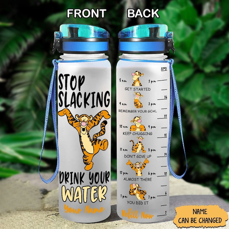 May include: A clear water bottle with a blue lid and a blue carrying strap. The bottle has a motivational quote that says "Stop Slacking Drink Your Water" with a cartoon tiger image. The back of the bottle has a motivational quote for each hour of the day with a cartoon tiger image for each hour.