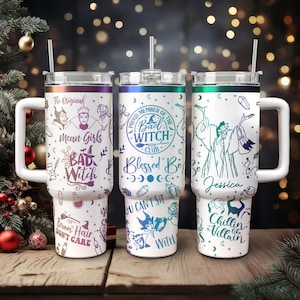 May include: Three stainless steel tumblers with colourful designs featuring a witch theme. The tumblers have a white background with black and purple illustrations. The text on the tumblers includes "The Original", "Mean Girls", "Bad Witch", "Proud Member of the Bad Witch Club", "Blessed Be", "You Can't Sit With", "Broom Hair Don't Care", "Jessica", "Chillin' Like a Villain".