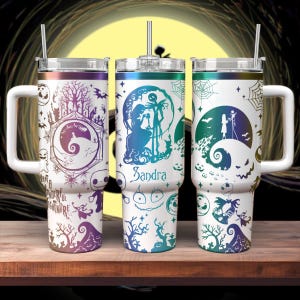 May include: Three white stainless steel tumblers with lids and straws. Each tumbler features a different design from the Nightmare Before Christmas movie. The designs include Jack Skellington, Sally, and the characters from the movie. The tumblers are decorated with a rainbow iridescent finish. One tumbler has the name "Sandra" on it.
