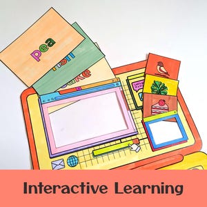 May include: A vibrant interactive learning set, featuring a paper laptop with open windows and flashcards. The flashcards display words like "pea," "fish," and "cake." Additional cards show a bird, a leaf, and a slice of cake. The phrase "Interactive Learning" is at the bottom.
