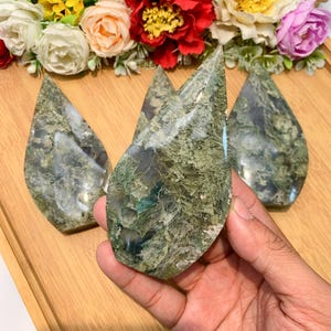 Könnte beinhalten: Vier grüne Moosachat-Tropfen. Die Steine sind poliert und haben ein natürliches, organisches Aussehen.