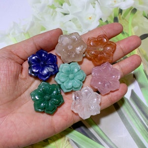 Peut inclure: Sept sculptures de cristal en forme de fleur dans différentes couleurs, notamment bleu, vert, rose, blanc et orange. Les sculptures sont présentées sur une main.