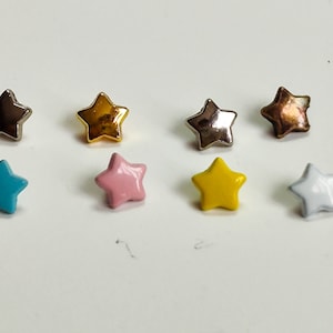 Può includere: Otto bottoni a forma di stella in vari colori, tra cui oro, argento, blu, rosa, giallo e bianco.