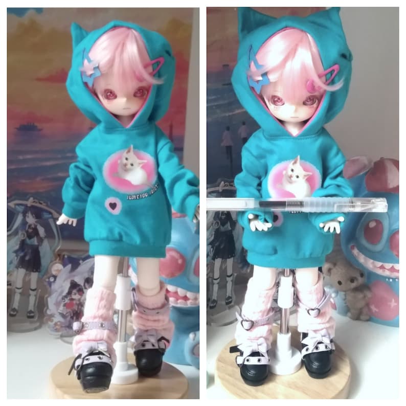 May include: A turquoise hooded sweatshirt with a pink cat graphic and the text "I love you most" on a doll with pink hair and white boots.