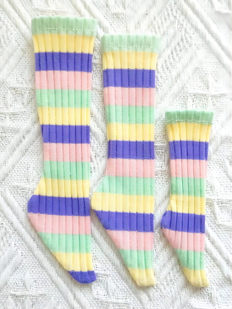 Pode incluir: Tr&ecirc;s pares de meias listradas em cores pastel, incluindo rosa, amarelo, verde e roxo. As meias est&atilde;o dispostas em uma fila do maior para o menor.