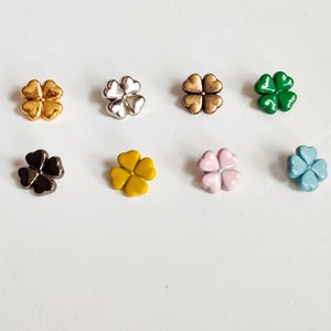Può includere: Otto ciondoli a forma di quadrifoglio in diversi colori: oro, argento, bronzo, verde, nero, giallo, rosa e blu.