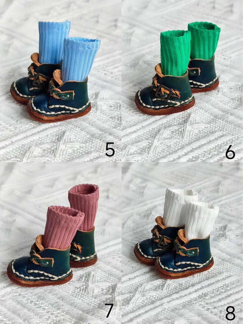 May include: Four pairs of miniature leather boots with different colored socks. The boots are dark blue with brown stitching and a buckle. The socks are light blue, green, pink, and white.