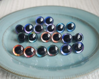 May include: Assortment of colorful plastic safety eyes for crafts. The eyes are various shades of blue, purple, red, and green with black pupils.