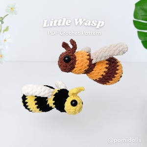 May include: Two crocheted bees with the text "Little Wasp PDF Crochet Pattern". One bee is brown, orange, and tan, the other is black, yellow, and white. The bees have large black eyes and are set against a white background.