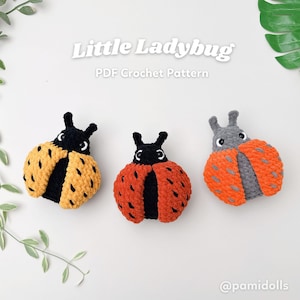 May include: Three crocheted ladybugs in yellow, red, and grey. Each ladybug has a black head with antennae and white eyes. The ladybugs are on a white surface. Text on the image reads "Little Ladybug PDF Crochet Pattern".