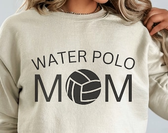 Op de afbeelding: Een beige sweatshirt met de tekst "WATER POLO MOM" in zwarte letters en een zwarte waterpolobal afbeelding.