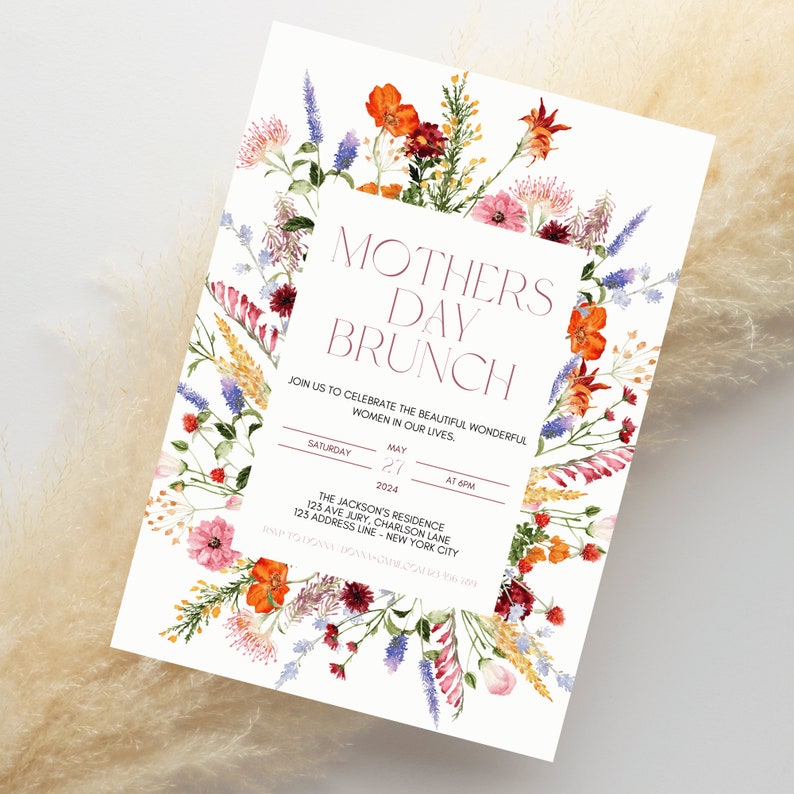 Pu&ograve; includere: Un invito per un brunch della festa della mamma con bordo floreale. L'invito presenta il testo "Mothers Day Brunch" e i dettagli dell'evento. Il bordo floreale comprende fiori arancioni, rossi, rosa e viola. Lo sfondo &egrave; bianco.