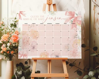 Puede incluir: Un calendario floral rosa y blanco con el texto "Guess the arrival of baby Jensen" en la parte superior. El calendario es para noviembre y diciembre y tiene los días de la semana etiquetados. Está en un caballete de madera.
