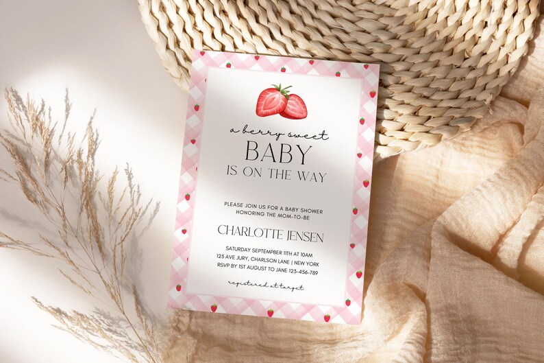 May include: A baby shower invitation with a pink gingham border and strawberry accents. The text reads "a berry sweet BABY IS ON THE WAY" with details for Charlotte Jensen's baby shower.