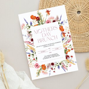 Pu&ograve; includere: Un invito bianco con il testo "Mothers Day Brunch" in bordeaux, circondato da un bordo floreale di fiori rossi, arancioni, rosa e viola. L'invito include i dettagli per un brunch il 21 maggio 2024, alle 18:00.
