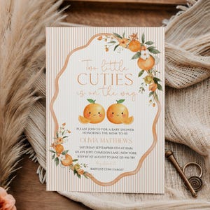 May include: Baby shower invitation with the text "Two little CUTIES is on the way." The invitation features orange illustrations and floral accents. The invitation includes the name Olivia Matthews, date, time, and location.