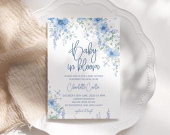 Puede incluir: Una invitación de baby shower azul y blanca con un diseño floral y el texto "Baby in Bloom". La invitación incluye el nombre "Charlotte Carter" y los detalles del evento, incluida la fecha, la hora y la ubicación.