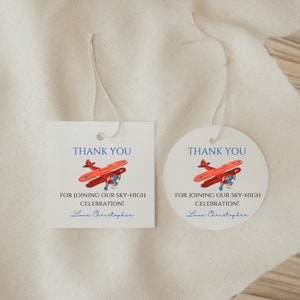 May include: Two white paper tags with string, one square and one round. Both tags feature a red airplane graphic and the text "THANK YOU" in blue. The tags read "FOR JOINING OUR SKY-HIGH CELEBRATION! Love Christopher."