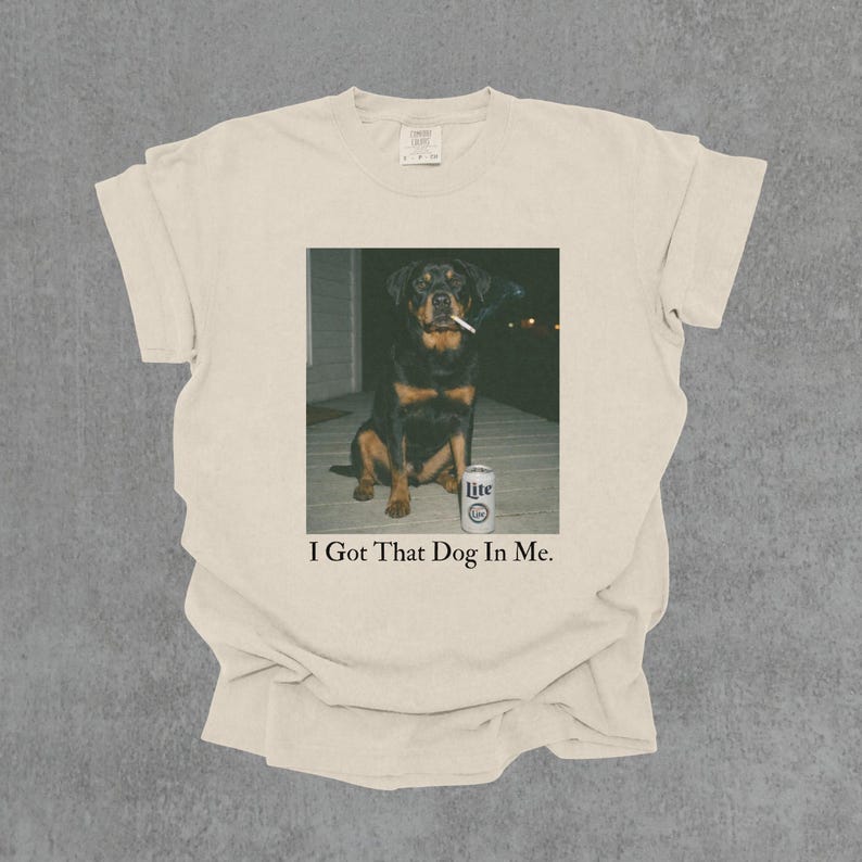 T-shirt featuring a retro-style photo of an unbothered Rottweiler sitting on a porch with humorous meme energy and the caption ‘I Got That Dog In Me'
