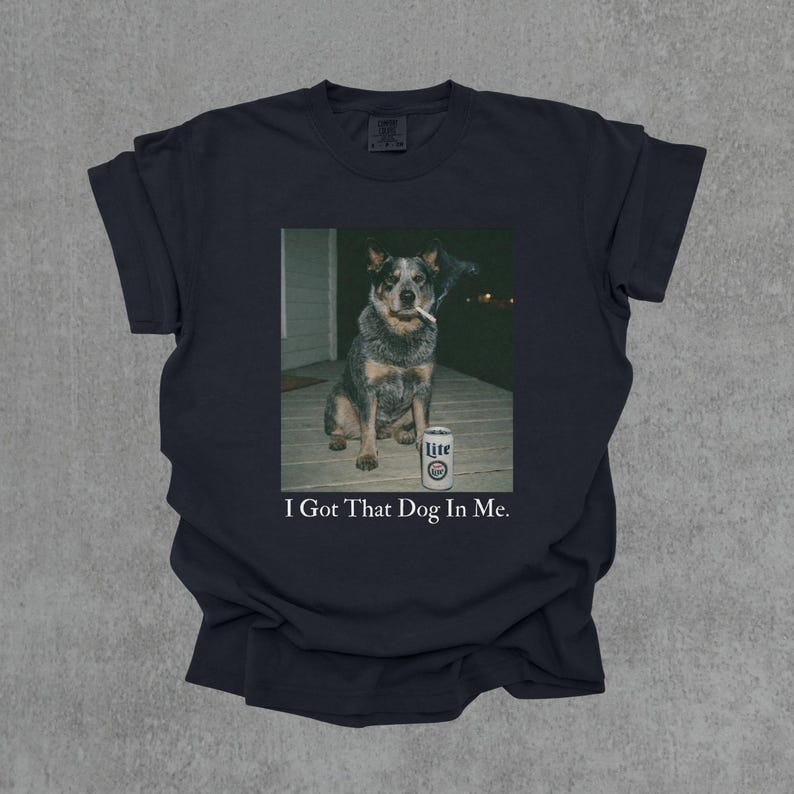 T-shirt featuring a retro-style photo of an unbothered australian cattle dog sitting on a porch with humorous meme energy and the caption ‘I Got That Dog In Me'