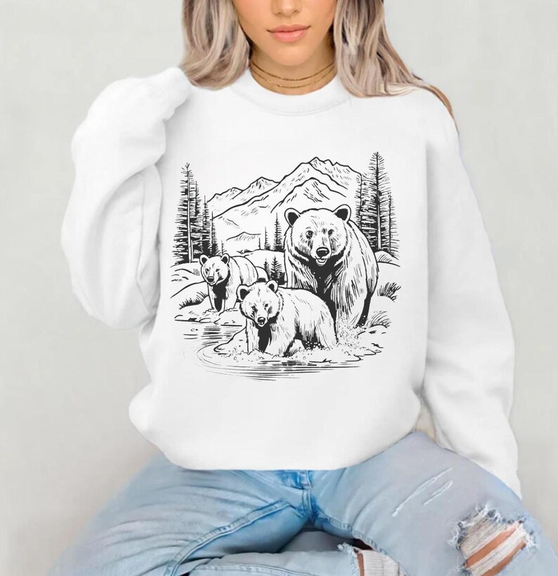 May include: White sweatshirt with a black and white illustration of three bears in a mountain landscape. The bears are standing in a stream of water.