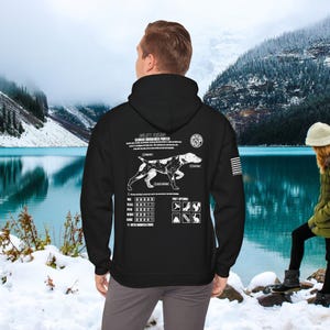 Può includere: Felpa con cappuccio nera con una grafica bianca di un Bracco tedesco a pelo corto con un diagramma delle sue caratteristiche e delle sue prede. Il testo "GSP" è in un cerchio sul lato destro della grafica.