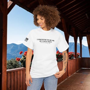 May include: White t-shirt with a black graphic that reads "I pretend to be ok but deep down I just want another cat".